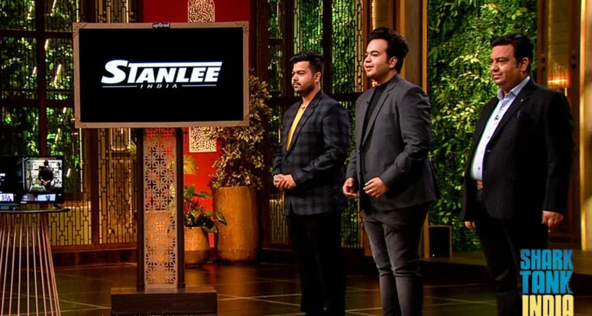 Amar Kant, Nimit and Mayank Luthra on the Shark Tank India stage, the Stanlee India mark on the screen beside them